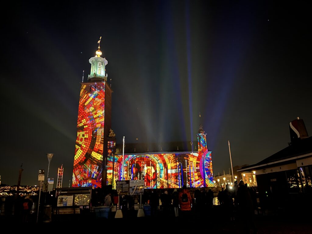 image shows Stockholm's City Hall projected with the Nobel Lights for the holiday season