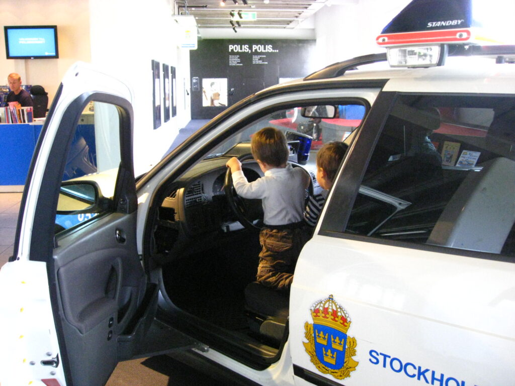 image shows two kids playing in a police car at the Polismuseet in Stockholm
